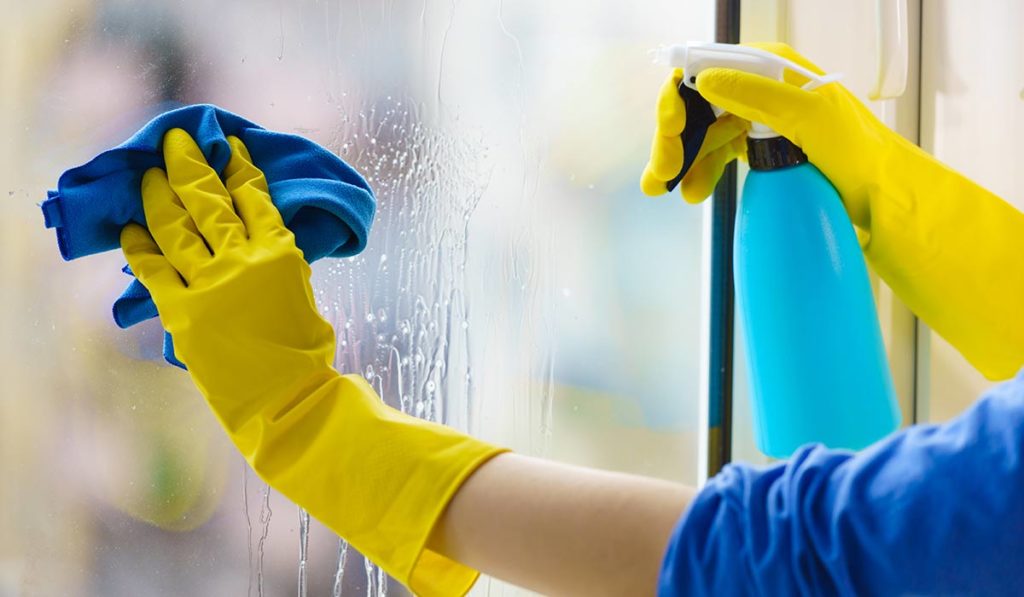 Frau reinigt Fenster mit Folierung.